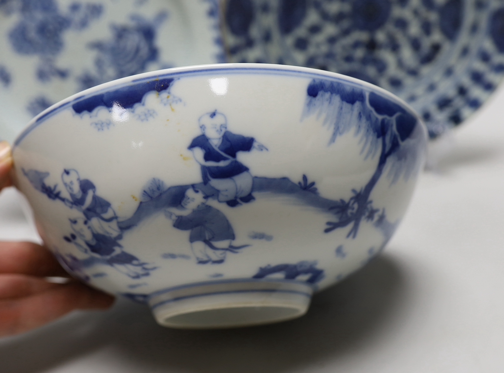 A Chinese blue and white ‘boys’ bowl and two blue and white flower plates, largest 24cm diameter